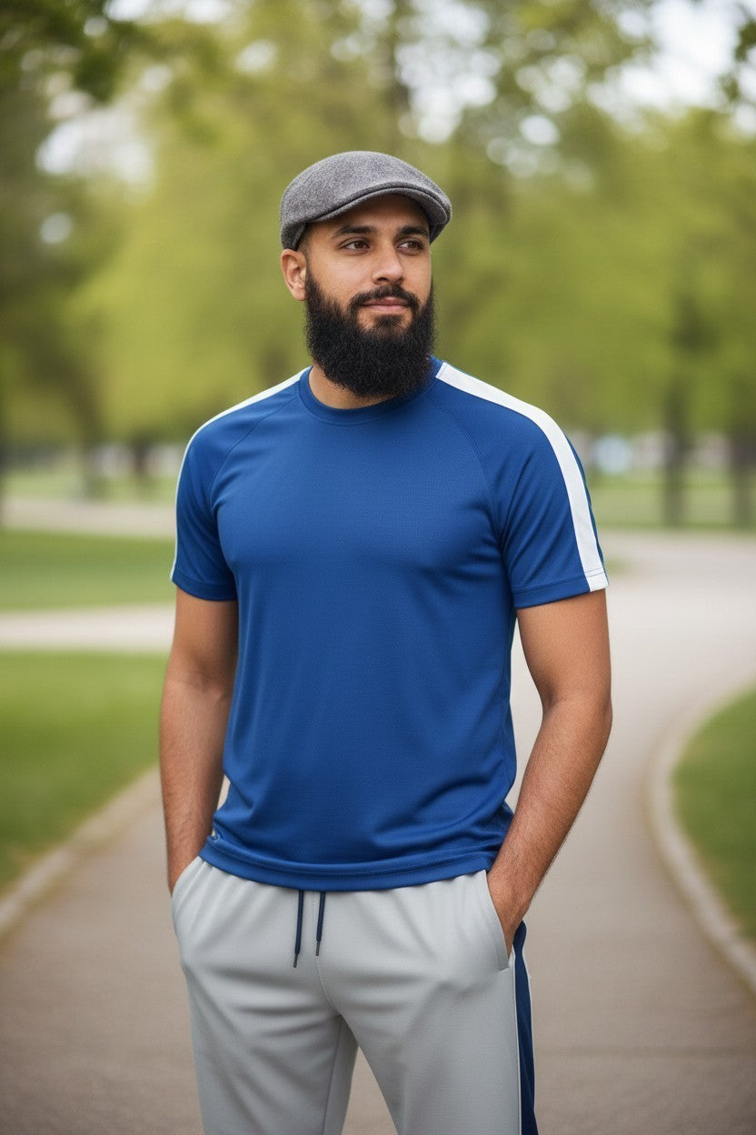 Sunnah Conscious navy blue and steel grey tracksuit with white side stripes worn by a bearded man in a park